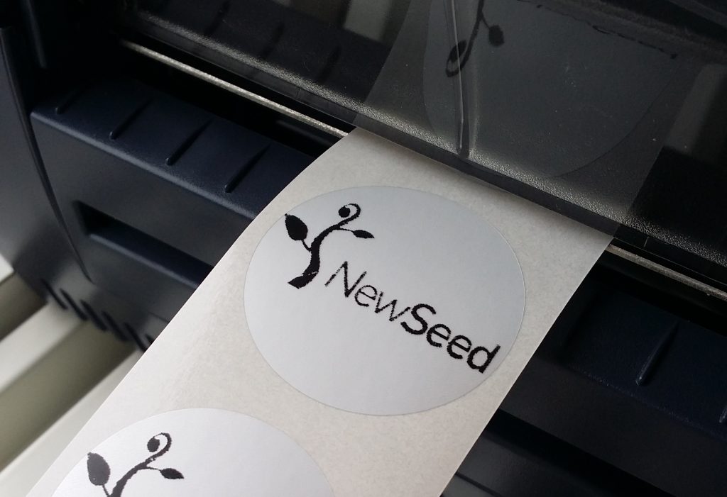 ZEBRA-utskrift av New Seeds logotyp på runt märke.